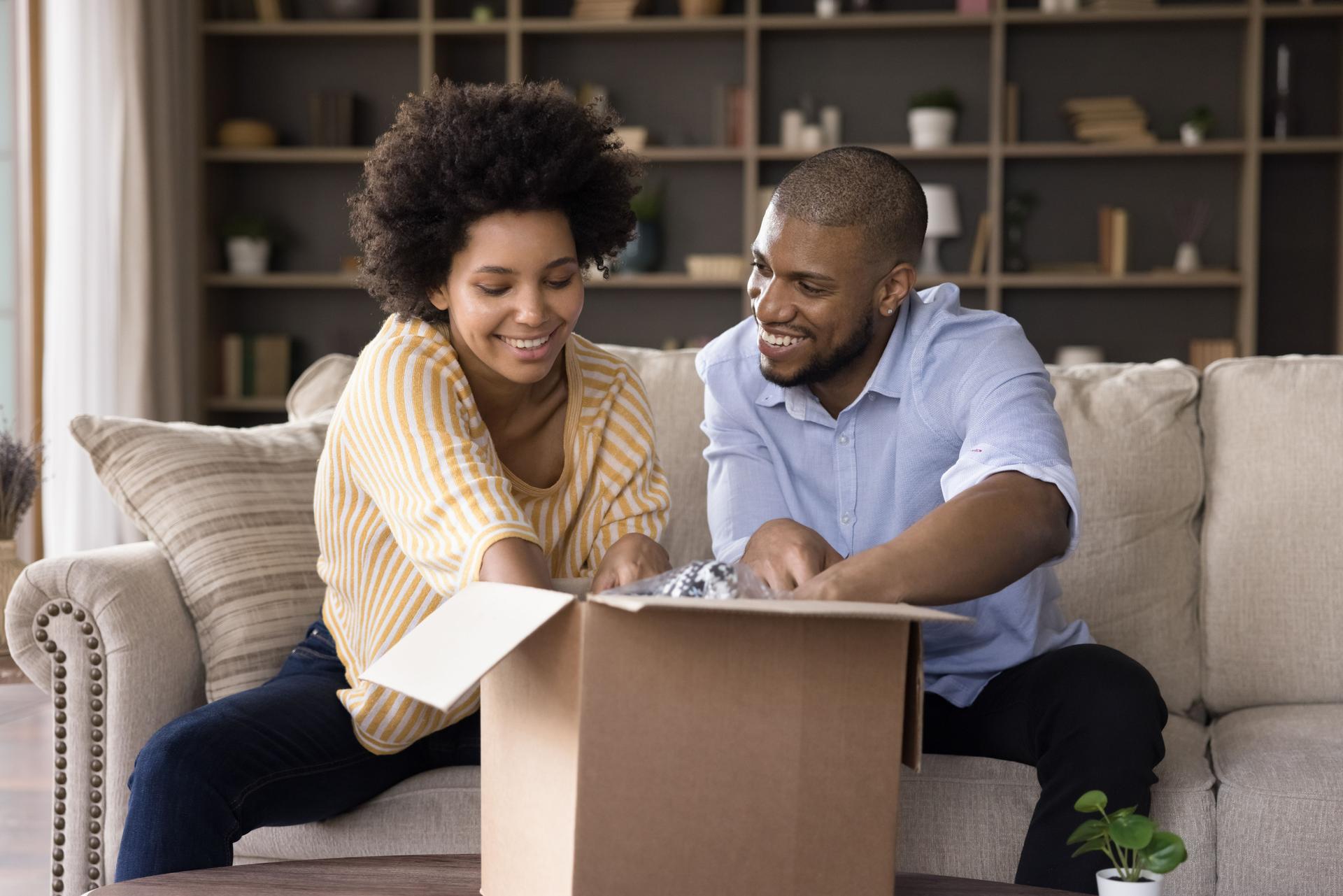 Happy african american couple unpacking parcel at home.